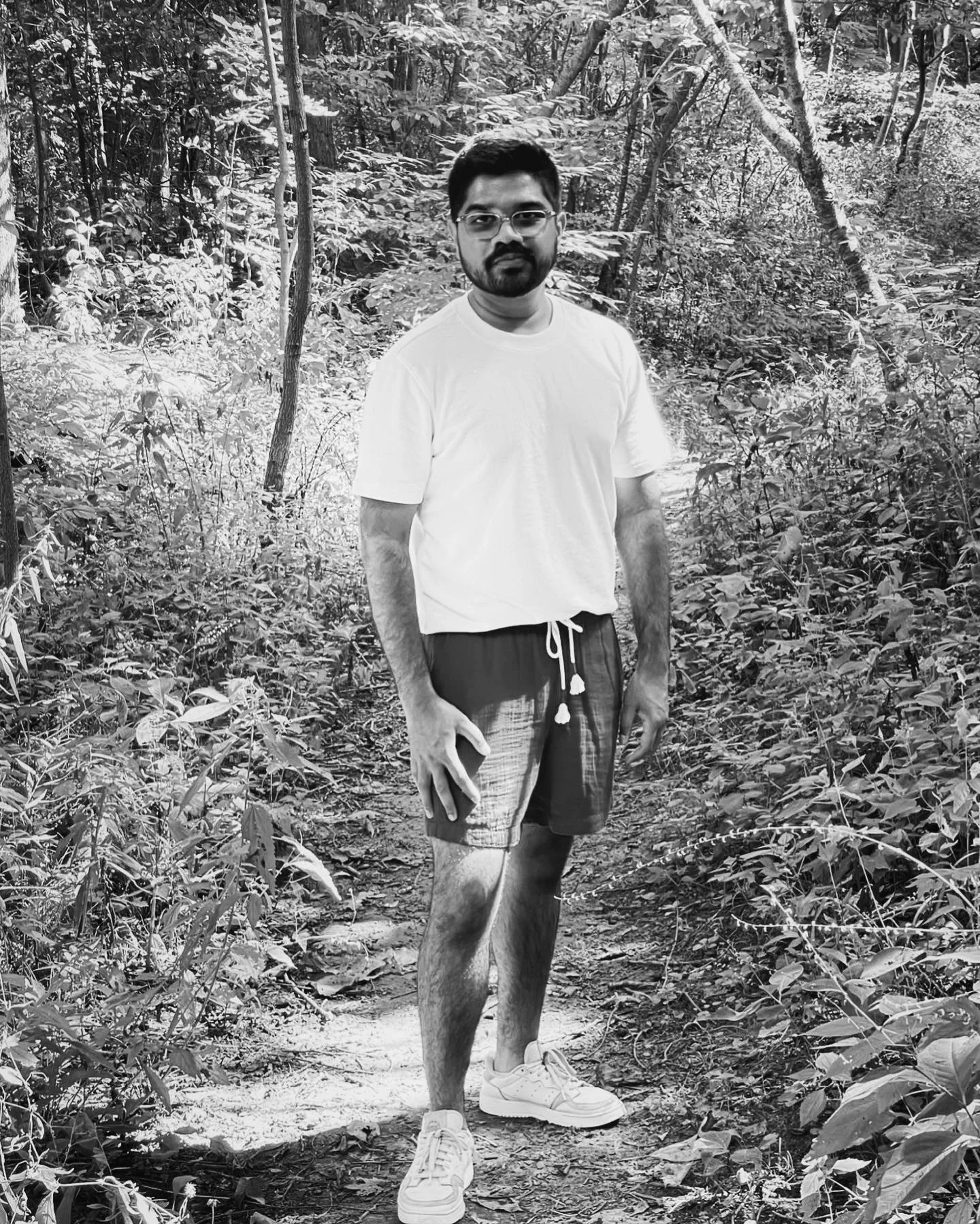 Black-and-white photograph of Arman Chowdhury standing on a wooded path